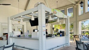 Un espace bar avec un comptoir, des luminaires suspendus et un panneau affichant le menu.