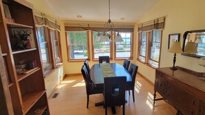 Un comedor con una mesa larga, sillas y un aparador de madera.