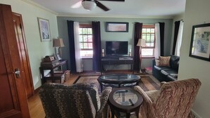 Una sala de estar con un sofá, sillones, una mesa de centro, un televisor y una chimenea.