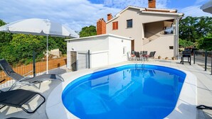 Une maison moderne à deux étages dotée d’une piscine, d’un espace salon extérieur et d’un patio couvert.