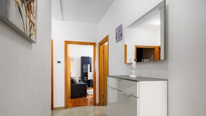 Un couloir avec une armoire blanche, un miroir et un tableau accroché au mur.