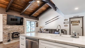 A modern kitchen with a stone wall, a built-in oven, a dishwasher, and a large sink.