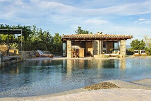 A poolside area with a stone structure, lounge chairs, and a clear view of the pool.