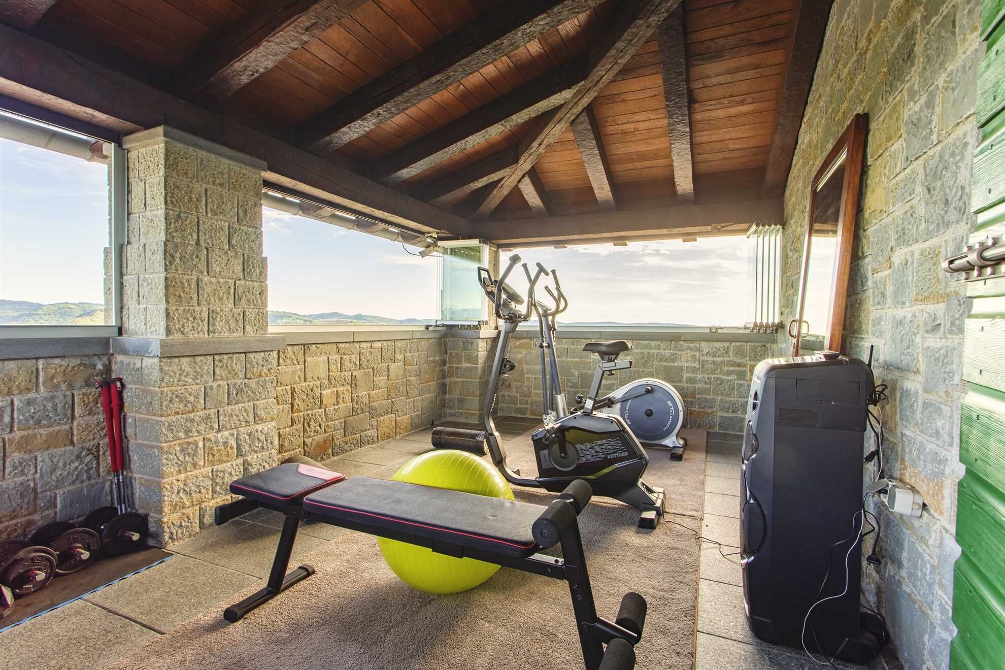 Un gimnasio al aire libre techado con equipo de ejercicio, una banca y una pesa rusa.