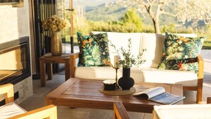 A cozy outdoor seating area with a wooden table, a sofa with tropical patterned cushions, and a vase with greenery. - Luxurious Villa Bora with a large 120 m Lagoon Pool and Waterfall (Buzet)