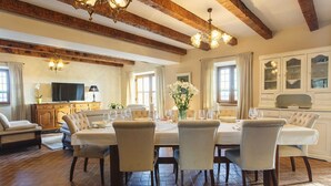 A dining area with a large table set for six, surrounded by six chairs. There is a television on a wooden cabinet to the left, and a cabinet with glass doors to the right. - Luxurious Villa Bora with a large 120 m Lagoon Pool and Waterfall (Buzet)