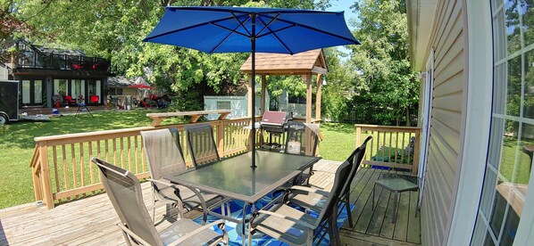 Un patio extérieur abrité, doté d’une table et de chaises, d’une terrasse en bois et d’un belvédère.