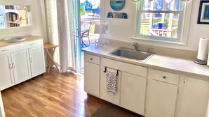 A small kitchen with a sink, cabinets, and a window overlooking a deck. - Bay Beach Cottage in Crystal Beach....perfect for a quiet getaway.  (Crystal Beach)
