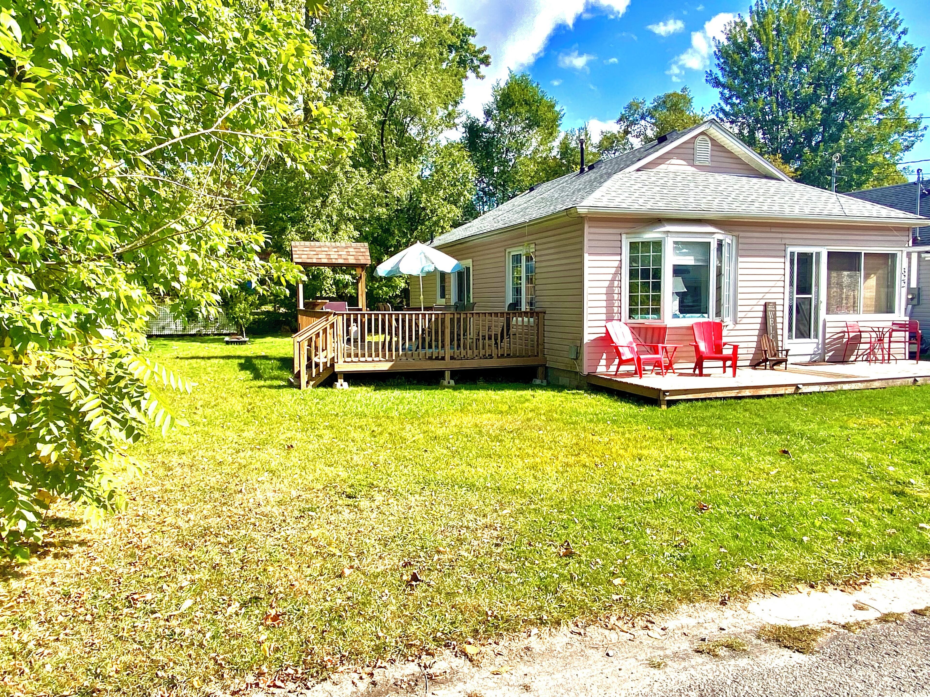 A small house with a deck, a covered patio, and a fenced yard.