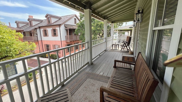 A covered porch with wooden benches and a view of neighboring houses. - Historic St. Augustine Balcony Apartment (Saint Augustine)