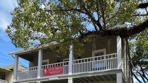 A two-story building with a porch, a banner advertising 'The Modern Rose All-Day Brunch & Coffee Cafe', and a 'We're Hiring' sign. - Historic St. Augustine Balcony Apartment (Saint Augustine)