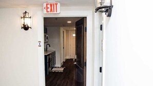 A hallway leading to a kitchen with an exit sign above the door. - Historic St. Augustine Balcony Apartment (Saint Augustine)