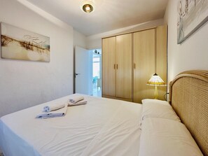 A hotel room with a bed, a wardrobe, a lamp, and a painting on the wall.