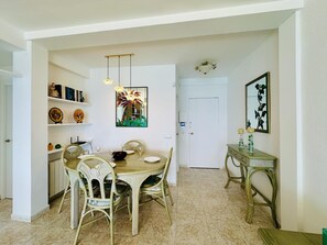 A dining area with a round table, chairs, and a hanging light fixture.
