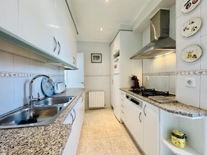 A kitchen with white cabinets, a granite countertop, a stainless steel sink, a gas stove, and a wall-mounted plate rack.