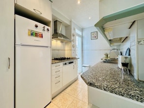 A kitchen with a refrigerator, stove, and granite countertop.
