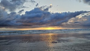 A beach with a sunset and cloudy sky.