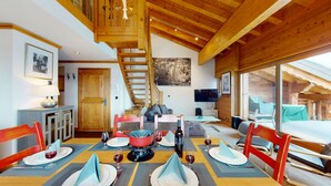 A dining area with a wooden ceiling, a staircase, a cityscape painting, and a television on the wall. - Terrasses du Paradis 7A LUXE & CENTER apart 7 pers (Haute-Nendaz)