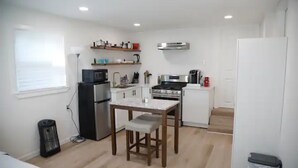 A compact kitchen with a refrigerator, stove, microwave, and a small dining table. - Small Studio - Trinity Groves - 5 Min Downtown (Dallas)