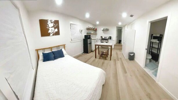 A bedroom with a bed, a desk, and a kitchenette. - Small Studio - Trinity Groves - 5 Min Downtown (Dallas)