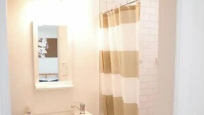 A bathroom with a white sink, mirror, and a shower curtain with a checkered pattern. - Small Studio - Trinity Groves - 5 Min Downtown (Dallas)