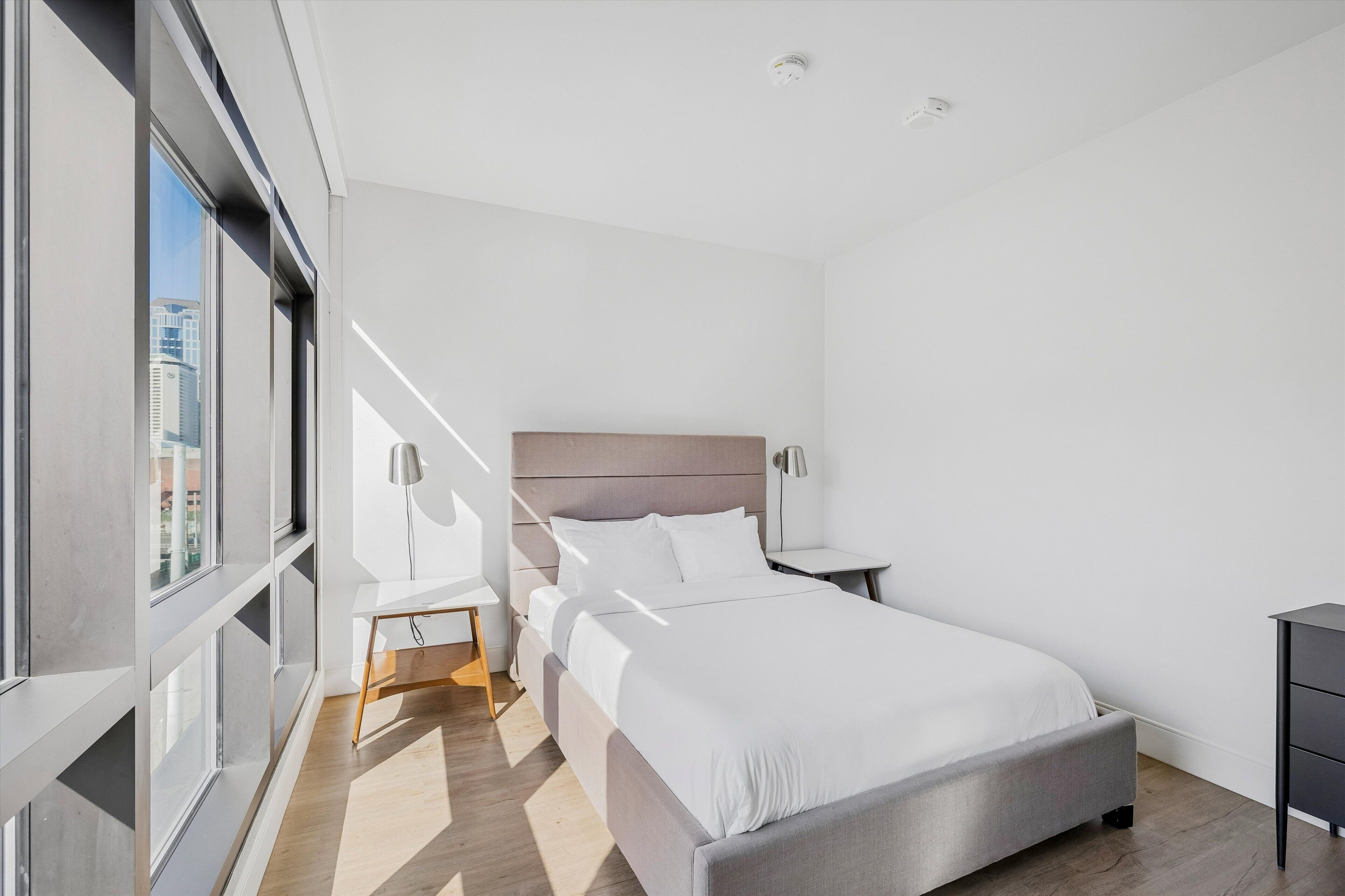 Una habitación de hotel moderna con una cama grande, mesitas de noche, un escritorio y una silla.