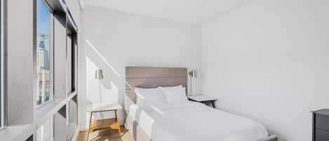 A modern hotel room with a large bed, bedside tables, a desk, and a chair.