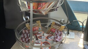 Un expositor metàllic de tres nivells amb diferents aliments envasellats per a esmorzar i col·lacions.