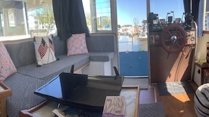 Un interior acollidor amb un sofà, una taula petita i una finestra amb vista a un cos d'aigua.
