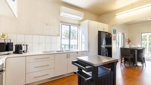 Eine moderne Küche mit weißen Schränken, einem Edelstahlkühlschrank, einer Kaffeemaschine und einem Fenster, das für natürliches Licht sorgt.