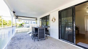 A balcony with a table and chairs, a sliding glass door, and a view of the neighborhood.