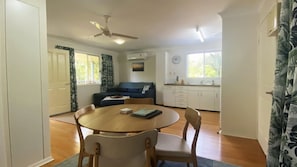 Ein Zimmer mit Esstisch, Stühlen, einer Couch, einem Deckenventilator und einem Fenster.