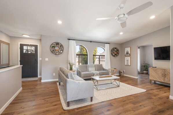 A spacious living room with a sofa, armchair, coffee table, and a TV.