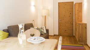 Ett mysigt vardagsrum med en trädörr, en lampa, en soffa och ett bord med en flaska och tallrikar.