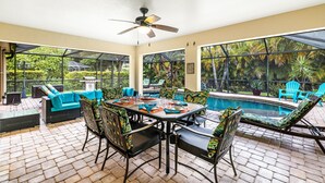 Eine sonnendurchflutete Terrasse mit Pool, Sitzgelegenheiten im Freien und einem Deckenventilator.