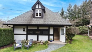 A house with a dark roof, white walls, and a small porch with two chairs.