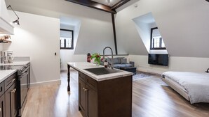 A modern loft bedroom with a large bed, a built-in desk, and a kitchen area.