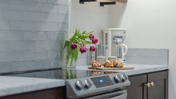 A kitchen with a modern design, featuring a marble countertop, a built-in oven, and a coffee maker.