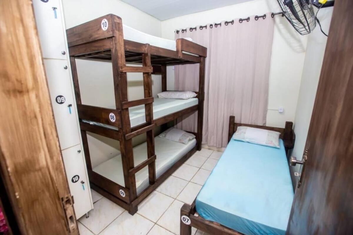 A bunk bed room with a single bed, a wardrobe, and a fan.