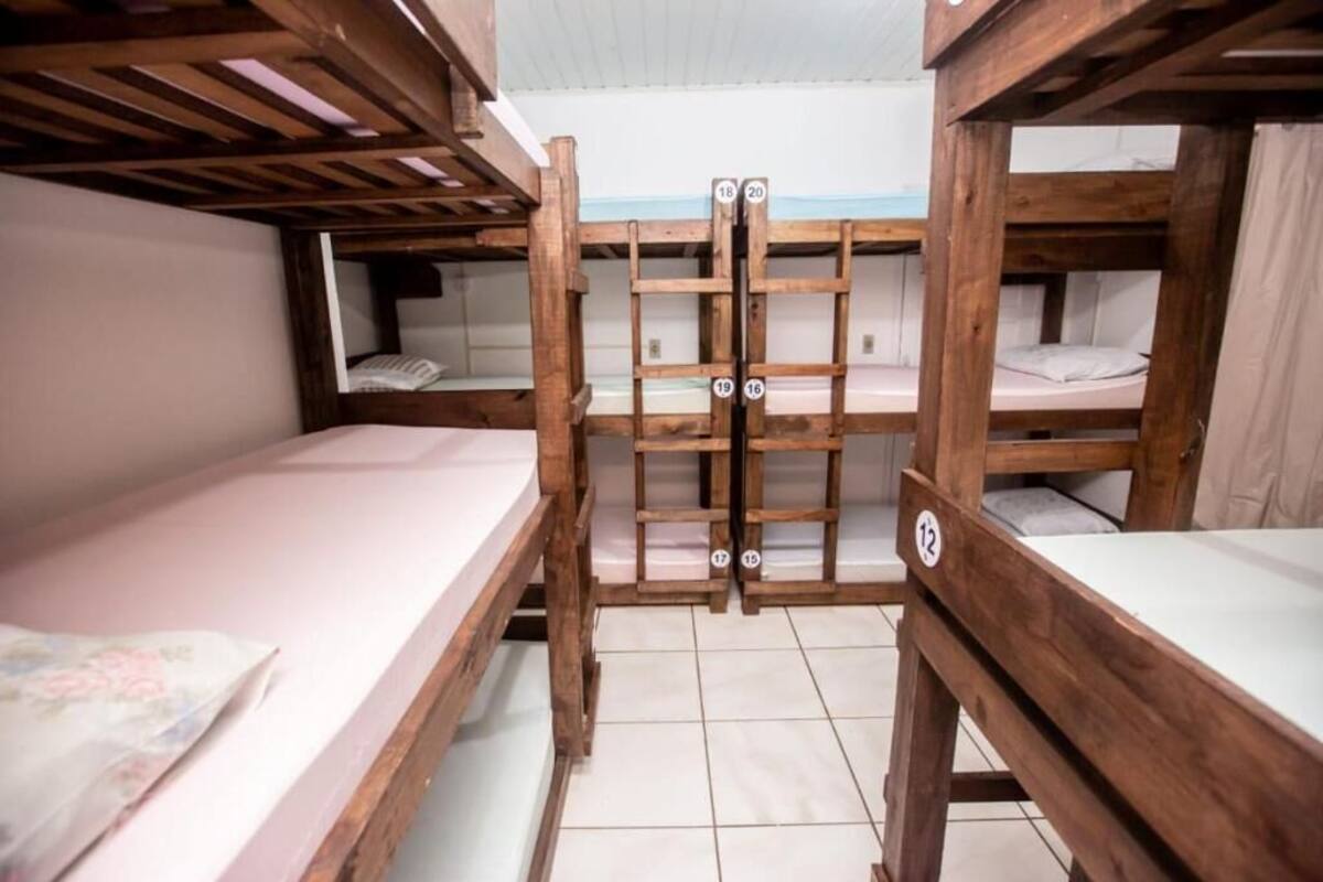 A dormitory room with bunk beds, wooden railings, and numbered beds.