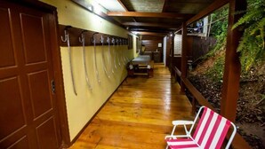 A wooden hallway with a bench and a chair, a door, and a row of hooks on the wall.