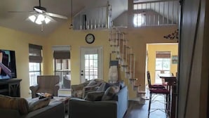 Una sala de estar con un sofá, un televisor y un ventilador de techo.