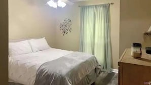 Un dormitorio con cama, ventilador de techo, decoración en la pared y ventana con cortinas.