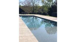 A rectangular swimming pool with a smooth, dark surface, surrounded by a light-colored deck. - Luxury cottage with pool (Charlottesville)