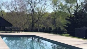 Una piscina rectangular con superficie lisa y oscura, rodeada por una terraza de color claro.