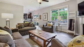 A modern living room with a wooden coffee table, grey sofas, and a ceiling fan. - Large luxe home with gorgeous outdoor spaces and hot tub (Fountain Inn)