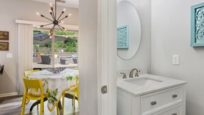 A modern bathroom with a white sink, a mirror, and decorative wall art. - Large luxe home with gorgeous outdoor spaces and hot tub (Fountain Inn)