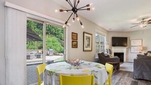 A dining area with a table set for four, a fireplace, and a television in a living room. - Large luxe home with gorgeous outdoor spaces and hot tub (Fountain Inn)
