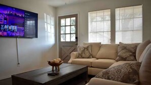 A living room with a sofa, a coffee table, and a TV mounted on the wall. - Cancun Street (Weslaco)