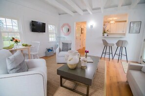 Un salon moderne avec un canapé, une table basse et un téléviseur. Il y a également un coin cuisine avec une table à manger et des chaises.